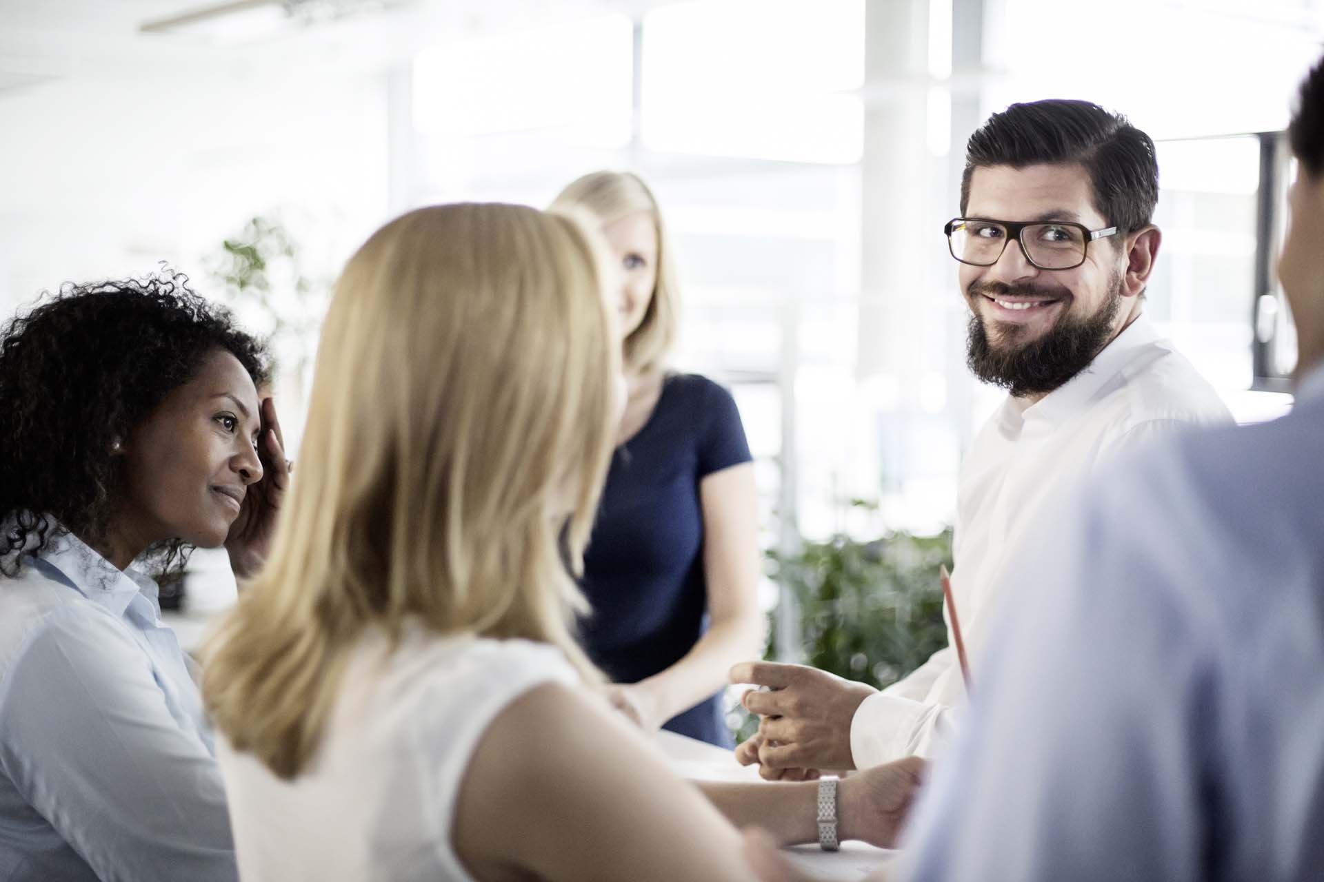 Homem sorrindo em grupo de colegas de trabalho