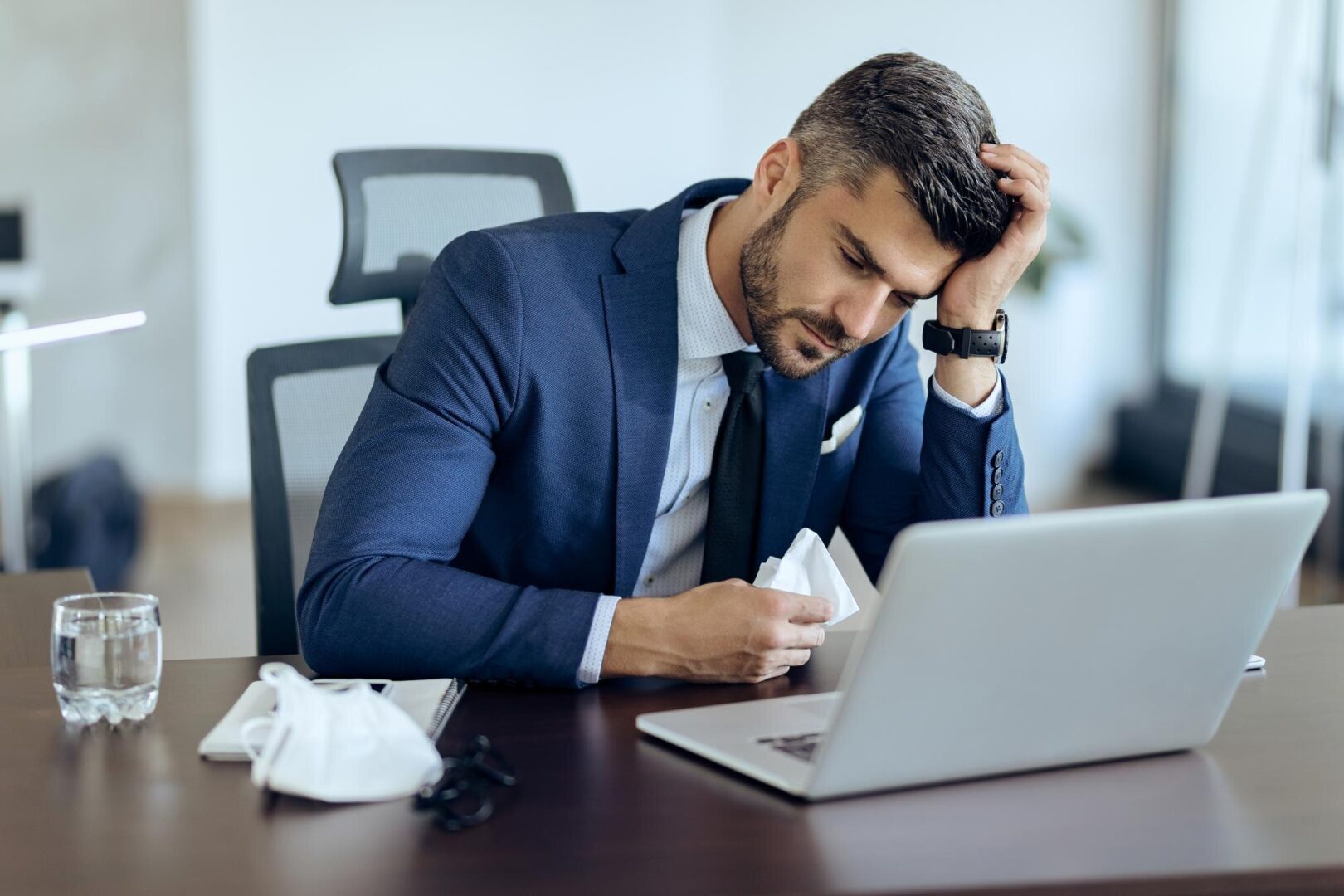 Empresário avalia falência corporativa em frente ao notebook.